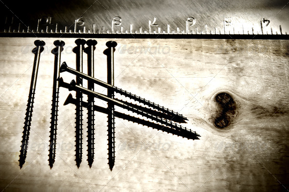 Screws and ruler on a grunge wood background