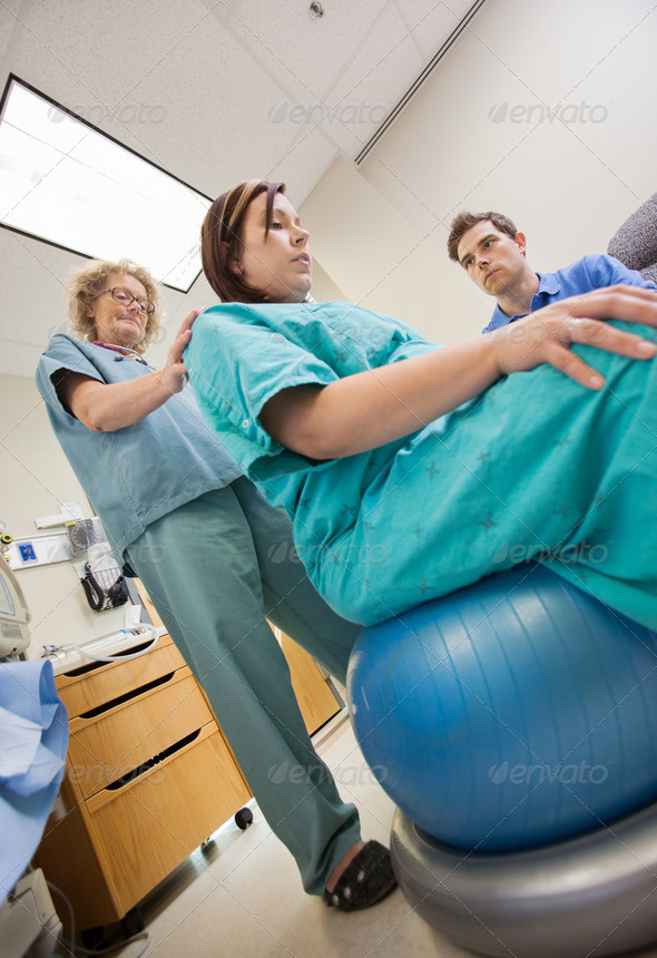 Nurse Assisting Pregnant Woman Sitting On Exercise Ball (Misc) Photo Download