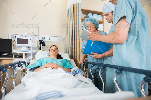 Nurses Discussing Patient's Report By Bed (Misc) Photo Download