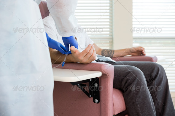 Nurse Adjusting IV Drip On Patient's Hand In Chemo Room (Misc) Photo Download