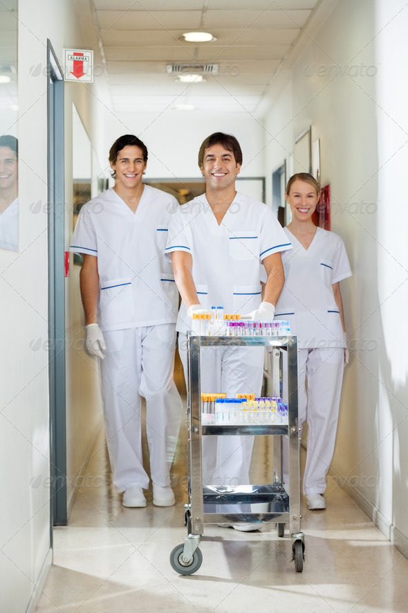 Technicians With Medical Cart Walking In Corridor