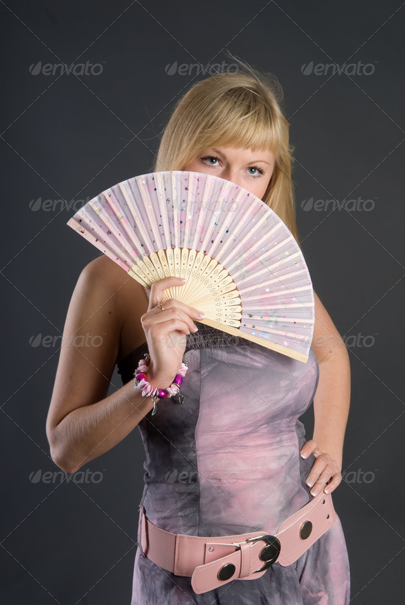 Attractive young woman with fan on black background