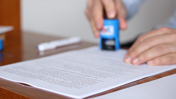 Man Signing and Stamping Documents Man Signing and Stamping Documents