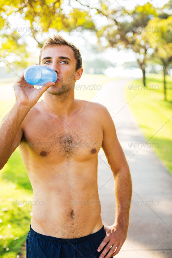 Athletic young man drinking water after workout