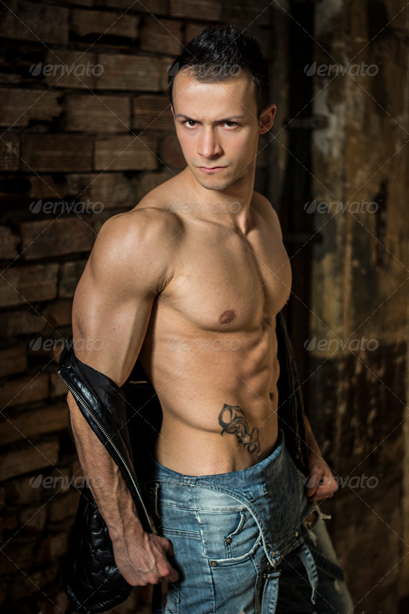 Muscular shirtless young man with jeans, indoors.