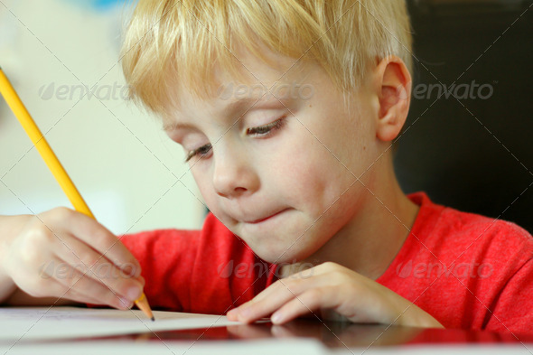 Young Child Drawing on Paper with Pencil