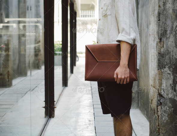 Man with leather bag on concrete wall