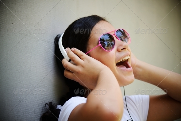Beautiful teenage girl listening to music on headphones and enjo