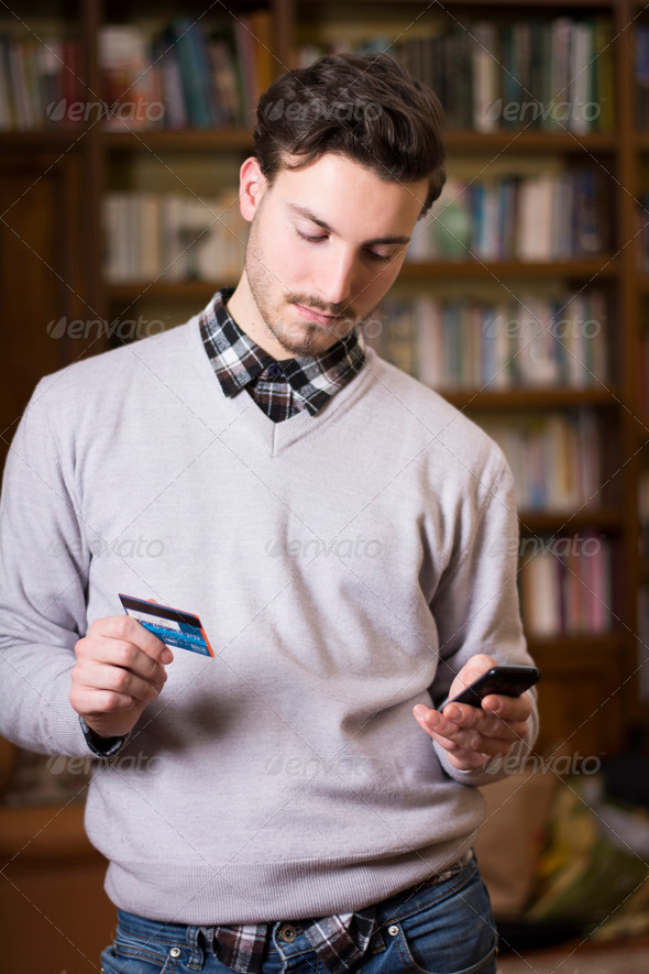 Attractive young man shopping online on mobile phone