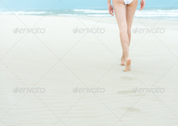Slim girl in white swimsuit walking to ocean.