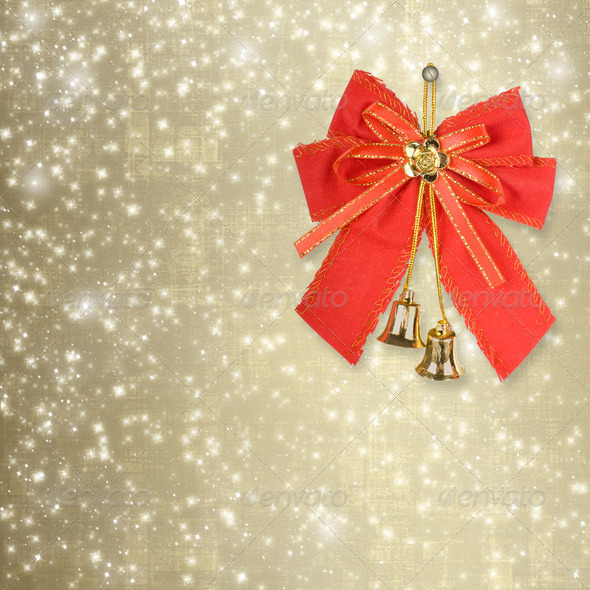 Red Christmas bow with golden bells on an abstract background