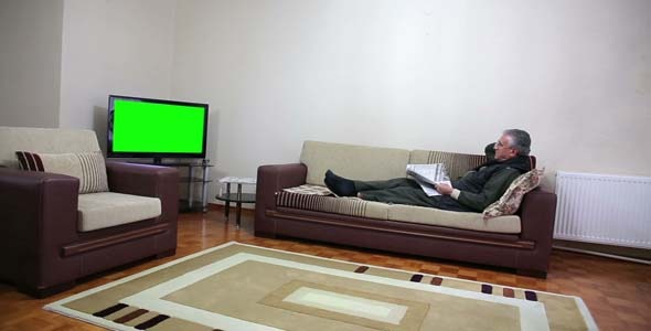 Senior Man Watching TV While Sitting On Sofa Senior Man Watching TV While Sitting On Sofa