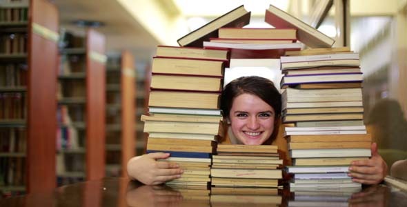 Student Gazing Through House-Shaped Stack Of Books Student Gazing Through House-Shaped Stack Of Books