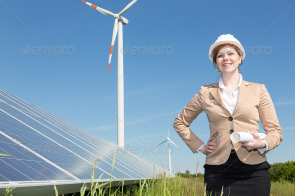 Engineer posing with wind turbine and solar panels