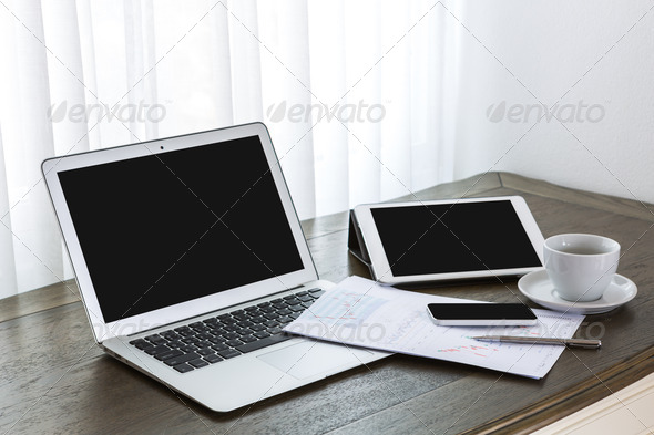Laptop, tablet , smartphone and coffee cup with financial docume
