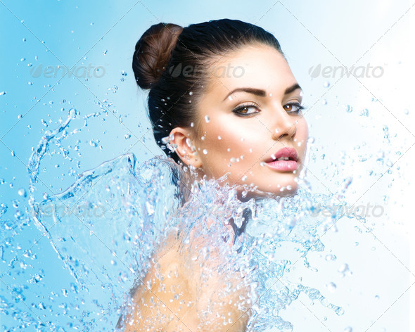 Beautiful girl under splash of water over blue background