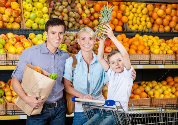 Happy family against shelves of fruits has shopping
