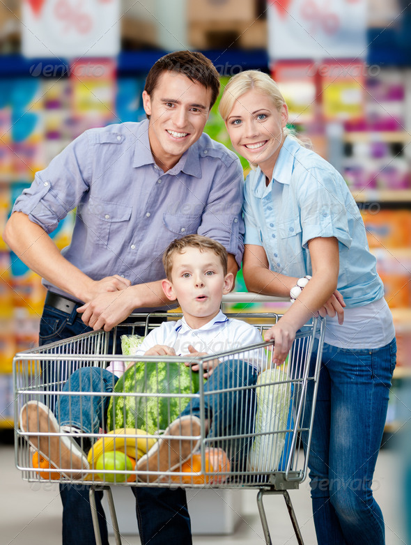 Family drives shopping trolley with food and boy sitting there