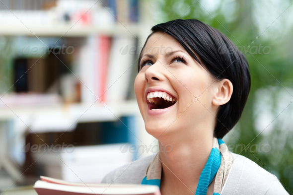 Laughing student with book at the library