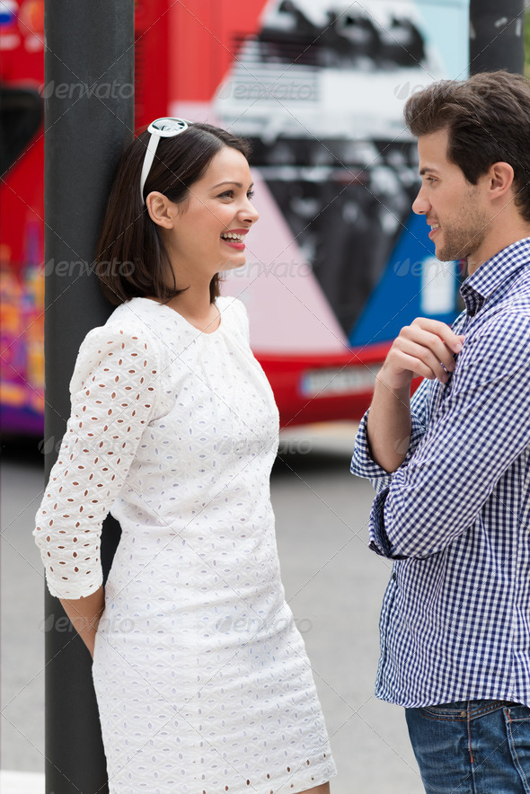 Stylish young couple standing talking in a street - Stock Photo - Images