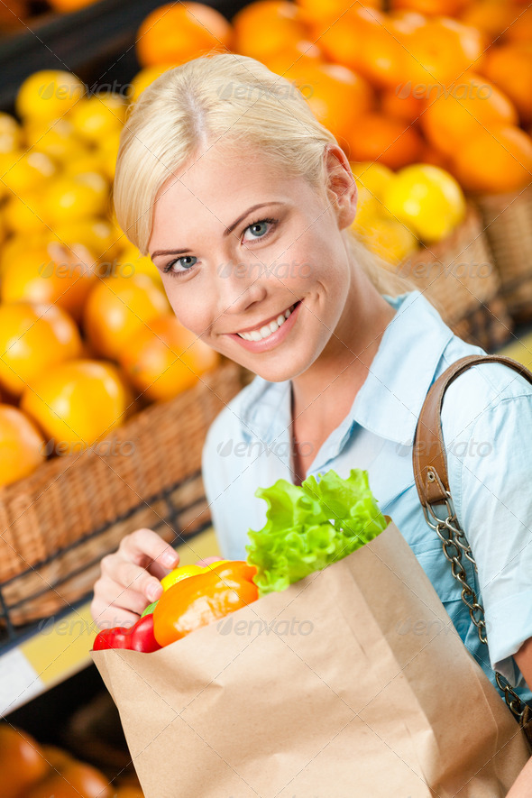 Girl holds paper bag with fresh vegetables