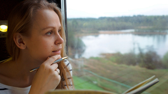 Young Woman Making Notes While Traveling By Train Young Woman Making Notes While Traveling By Train