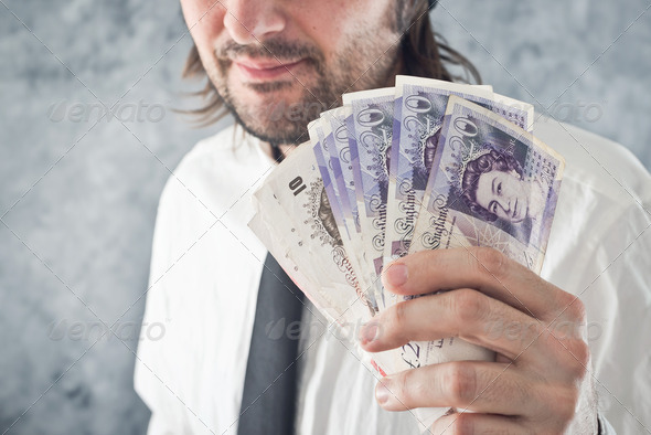Businessman holding British pounds money