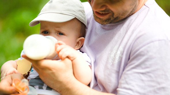 Young Father Feeding His Baby From The Bottle Young Father Feeding His Baby From The Bottle