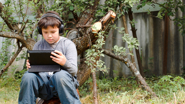Teenager In Earphones Using Touchpad Outdoor Teenager In Earphones Using Touchpad Outdoor