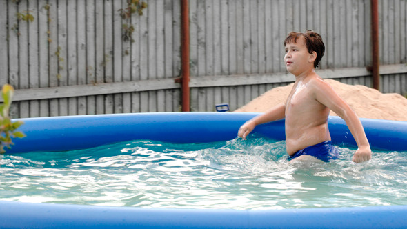 Boy Swimming In Inflatable Pool In The Yard Boy Swimming In Inflatable Pool In The Yard