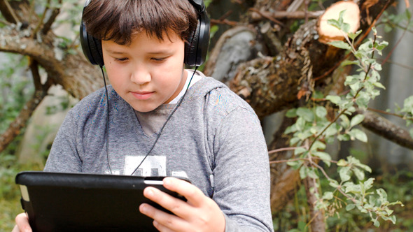 Boy In Headphones With Touchpad Outdoor Boy In Headphones With Touchpad Outdoor