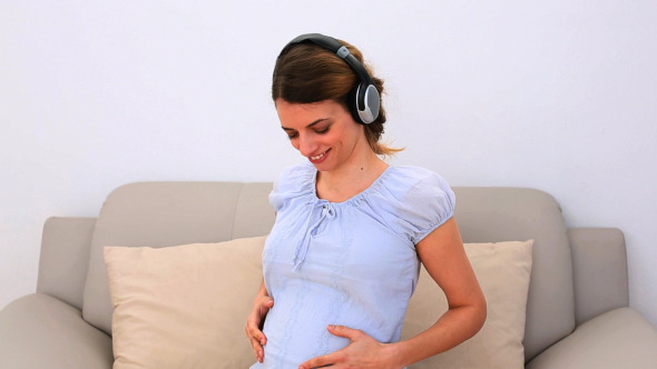 Pregnant Woman Listening To Music On The Couch Pregnant Woman Listening To Music On The Couch