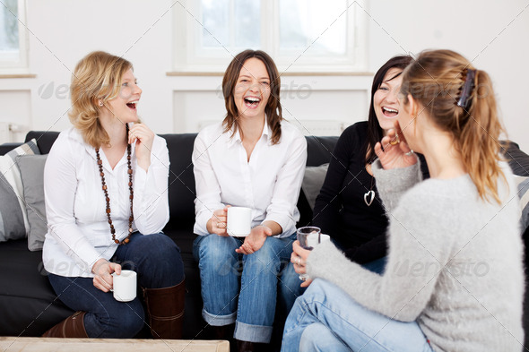 Friends Holding Coffee Cups While Laughing On Sofa