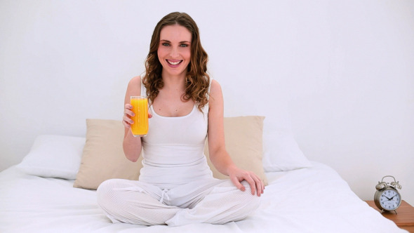 Pretty Model Sitting On Bed Drinking Orange Juice
