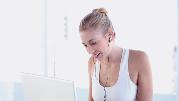 Sporty Blonde Using Laptop And Listening To Music