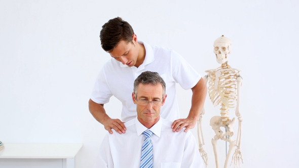Physiotherapist Giving Businessman A Shoulder Rub Physiotherapist Giving Businessman A Shoulder Rub