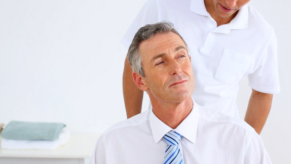 Physiotherapist Giving Businessman A Neck Massage Physiotherapist Giving Businessman A Neck Massage