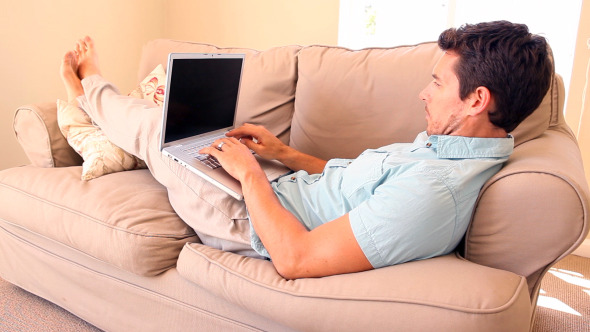 Man Lying On Couch Typing On Laptop Man Lying On Couch Typing On Laptop
