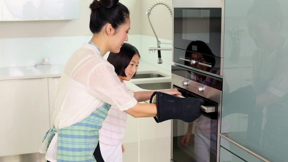 Mother Taking Baking Tray Out Of Oven Mother Taking Baking Tray Out Of Oven
