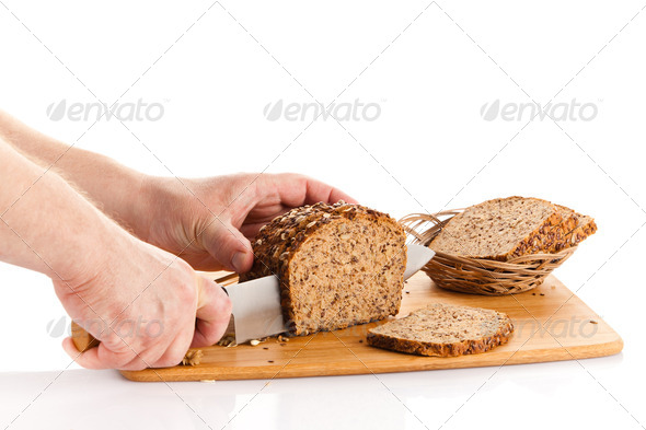 Fresh bread. Slicing Bran Bread on a Cutting Board. hands cutt (Misc) Photo Download