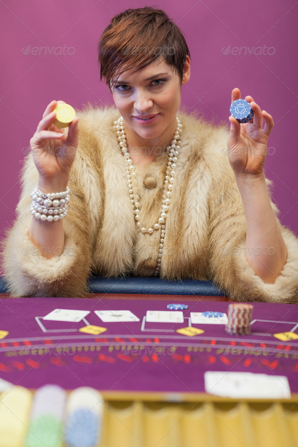 Woman holding up chips at poker game in casino (Misc) Photo Download