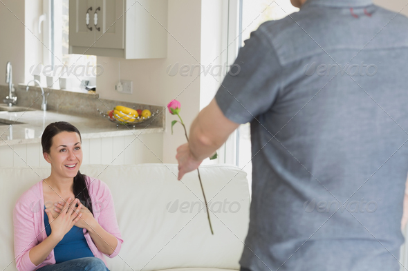 Woman getting a flower from husband in living room (Misc) Photo Download