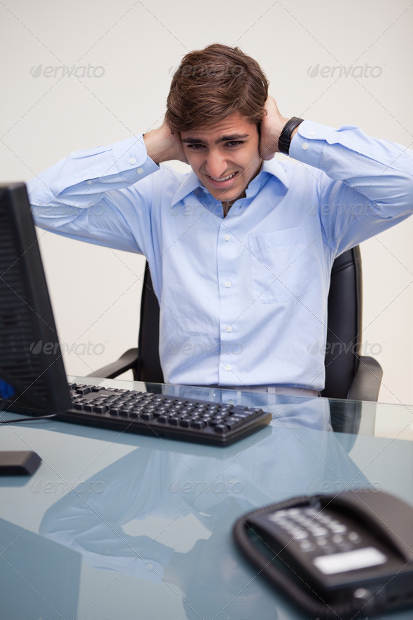 Young business man covering ears at office desk in office (Misc) Photo Download