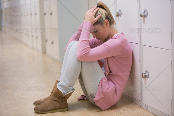 Upset student sitting on floor of hallway against lockers (Misc) Photo Download