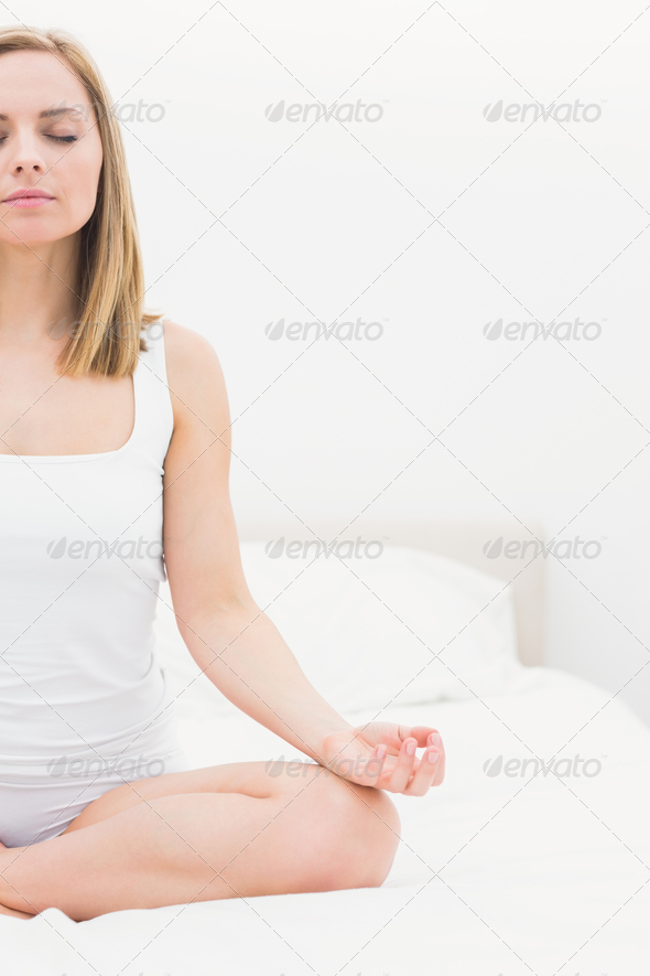 Young woman sitting in lotus position with eyes on bed at home (Misc) Photo Download