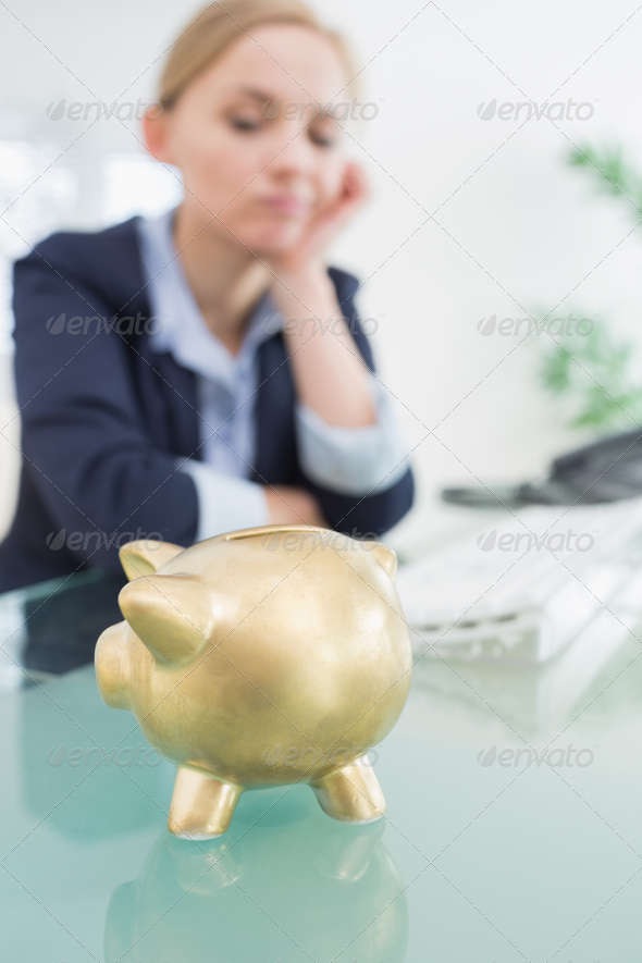 Upset business woman with piggy bank sitting at desk in office (Misc) Photo Download