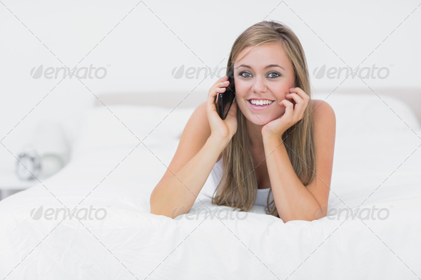 Cheerful woman phoning lying on the bed in the bedroom (Misc) Photo Download