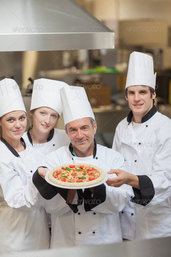 Four Chef's holding a pizza while smiling (Misc) Photo Download