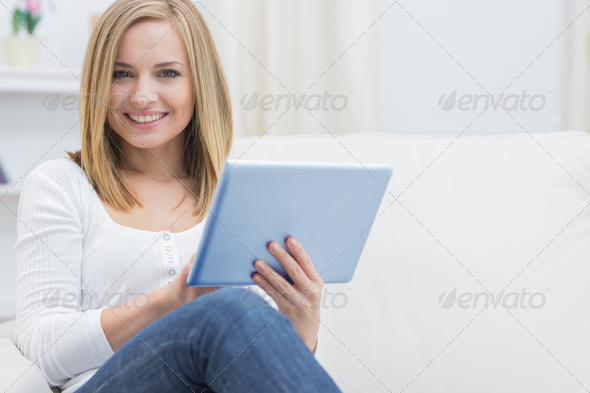 Portrait of casual happy young woman using digital tablet on sofa at home (Misc) Photo Download