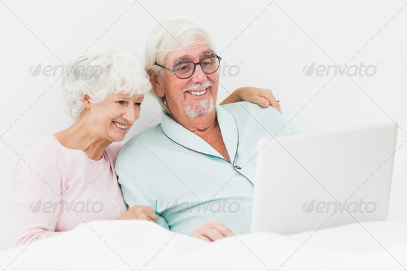 Elderly couple using laptop in bed (Misc) Photo Download